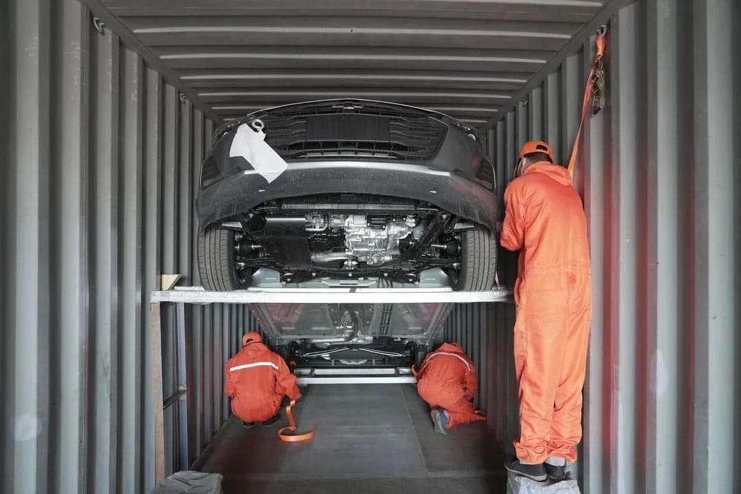 Workers fixing wheel chocks and lashings in a container